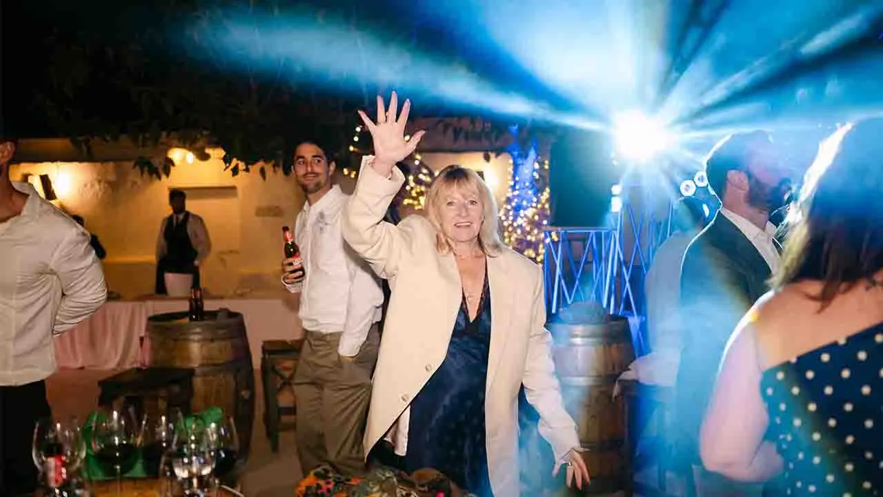 Festa di matrimonio all'aperto di sera in Italia con invitati che ballano sotto le luci e postazione DJ set senza limiti di orario.